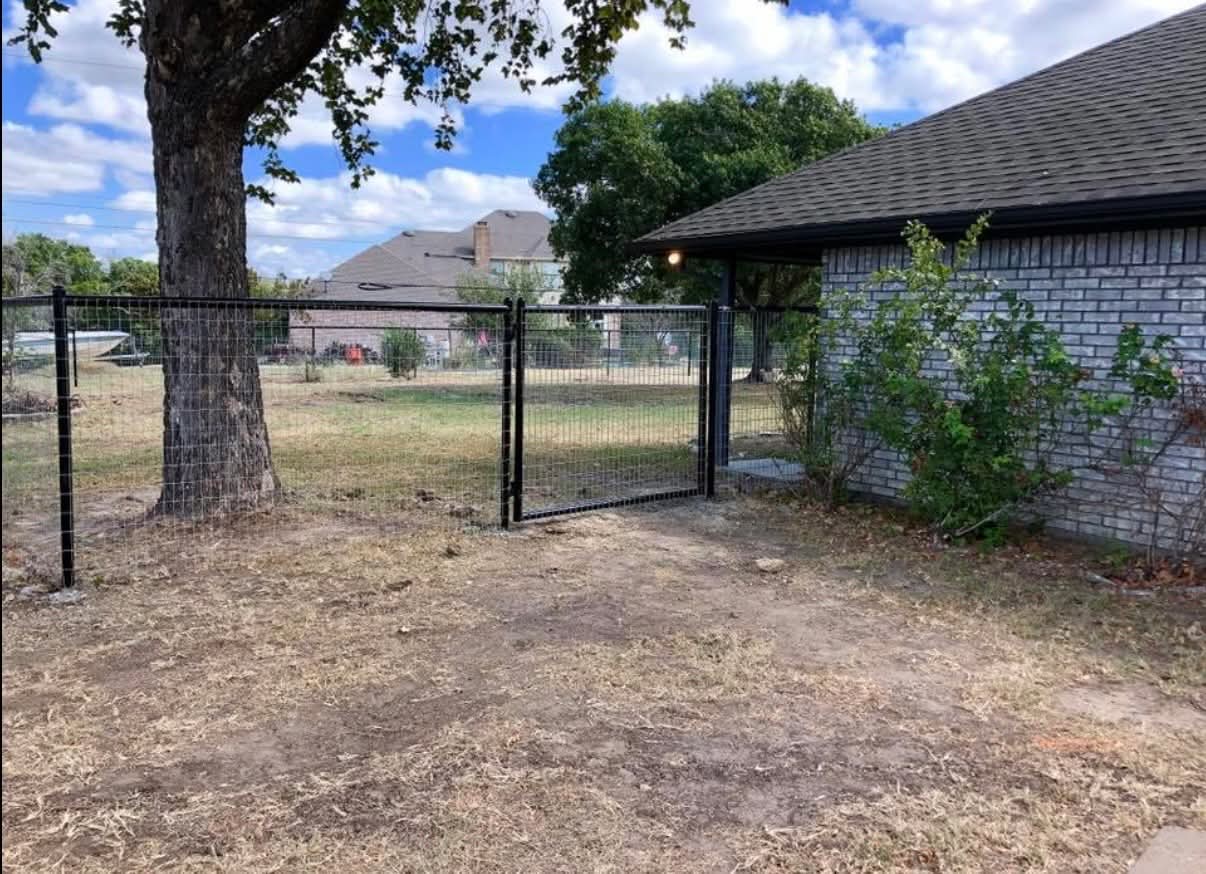 Black wire fence with a walk gate beside a shaded backyard